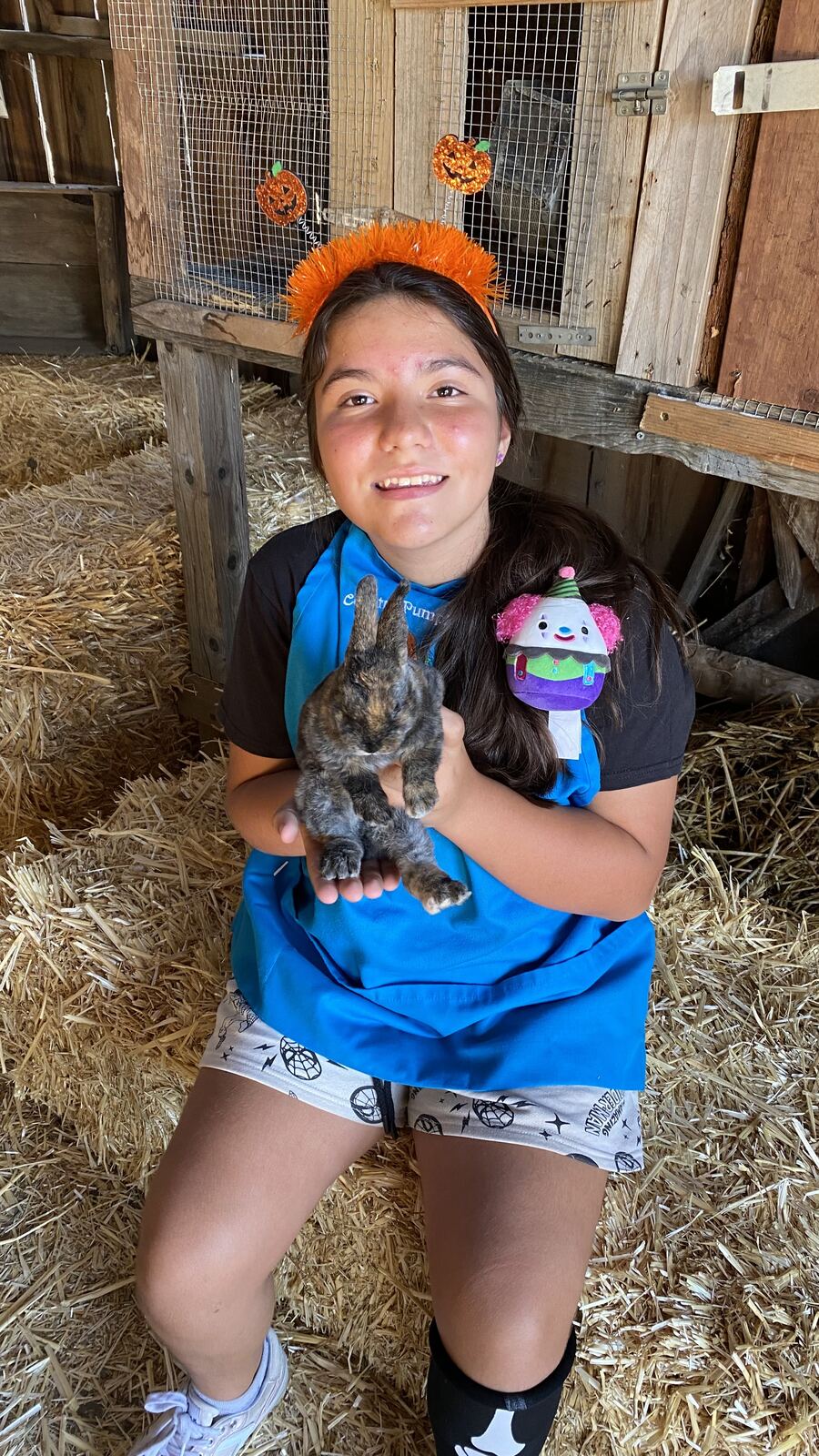 A young visitor in a pumpkin headband holding a rabbit in the Critter Corral